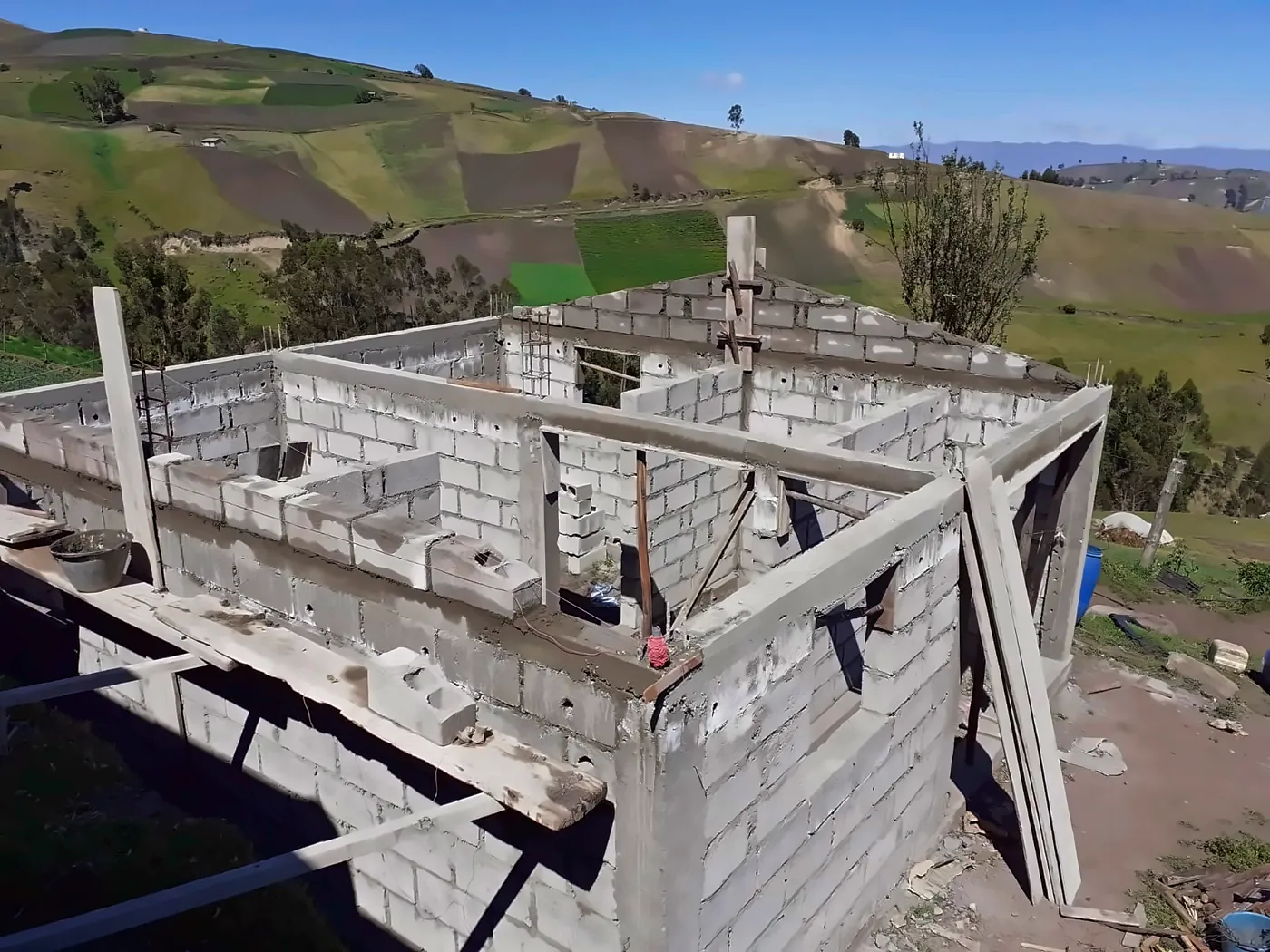 Casa in blocchi con travi in cemento completate, cielo azzurro