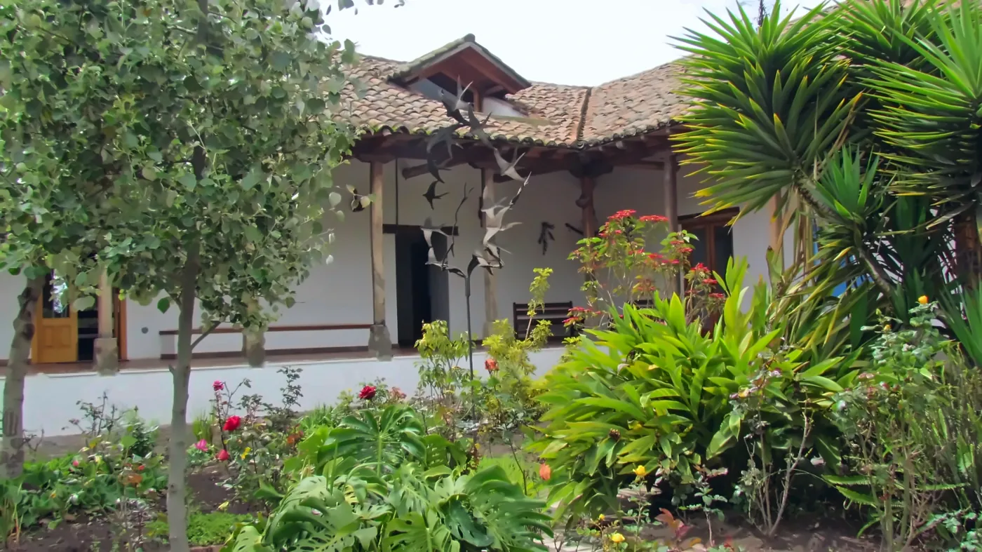 Portico bianco con tetto di coppi e un giardino fiorito
