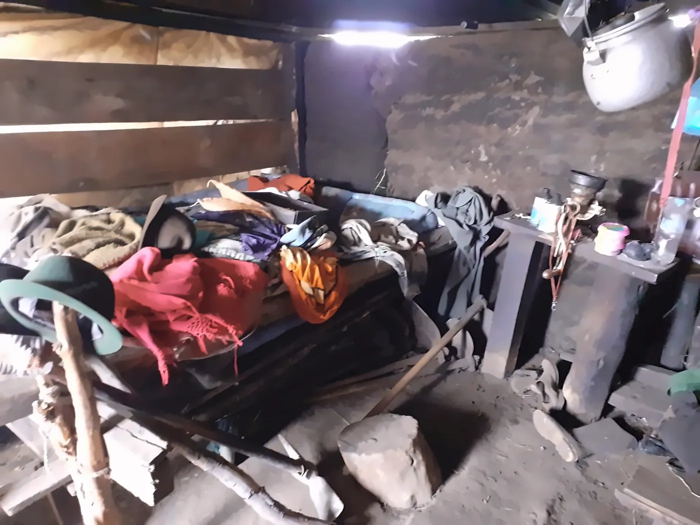 Interno buio di una capanna con un letto coperto di vestiti
