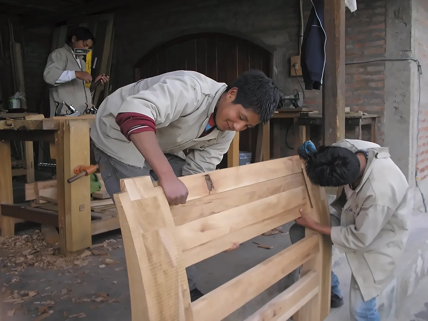Due ragazzi in camice da laboratorio montano una panca di legno massello