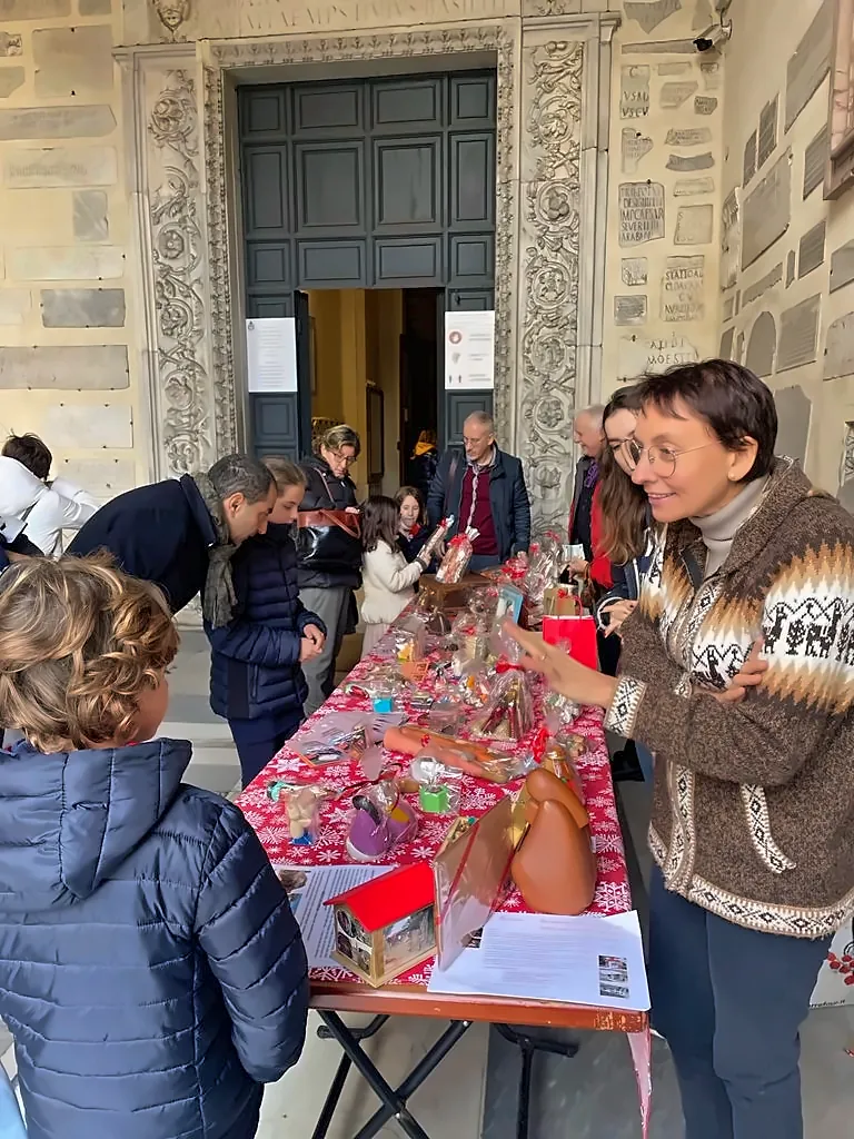 Banco del mercatino davanti al portale di una chiesa, con famiglie che guardano gli oggetti