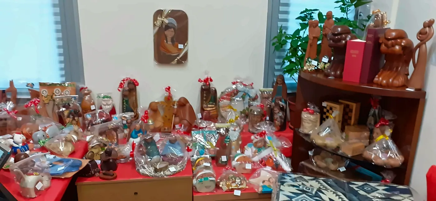 Banco del mercatino con sculture in legno, presepi e confezioni regalo