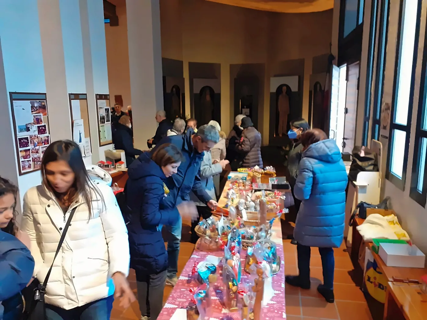 Lunga tavola di oggetti natalizi in una sala, con molte persone
