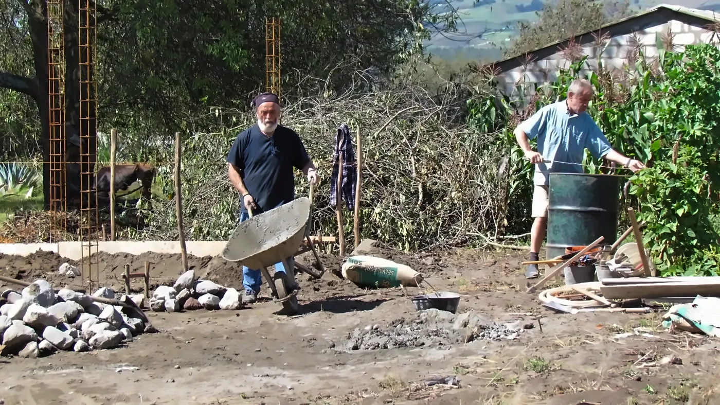 Peppo spinge una carriola di cemento in un cantiere
